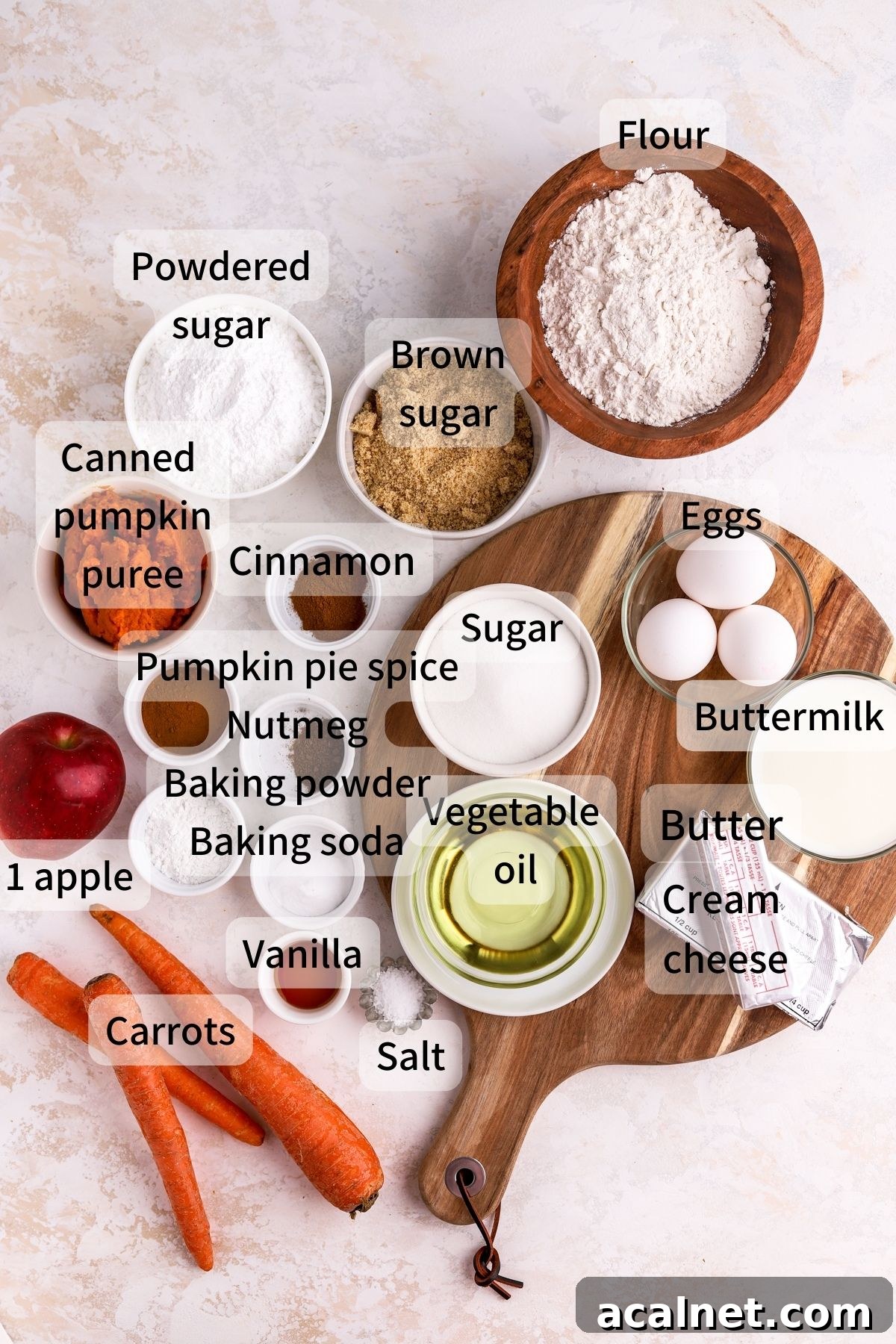 Labeled ingredients needed to make pumpkin carrot cake laid out on a table. 