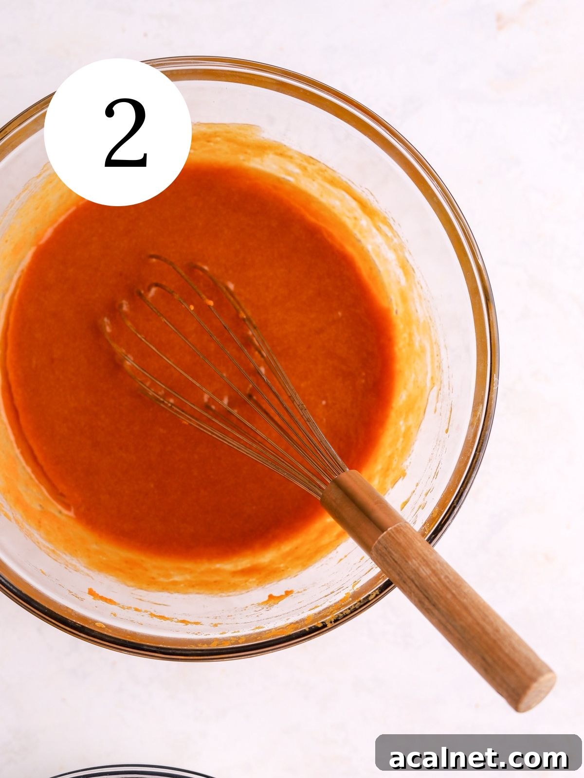 A mixing bowl with pumpkin puree and other wet ingredients whisked together.