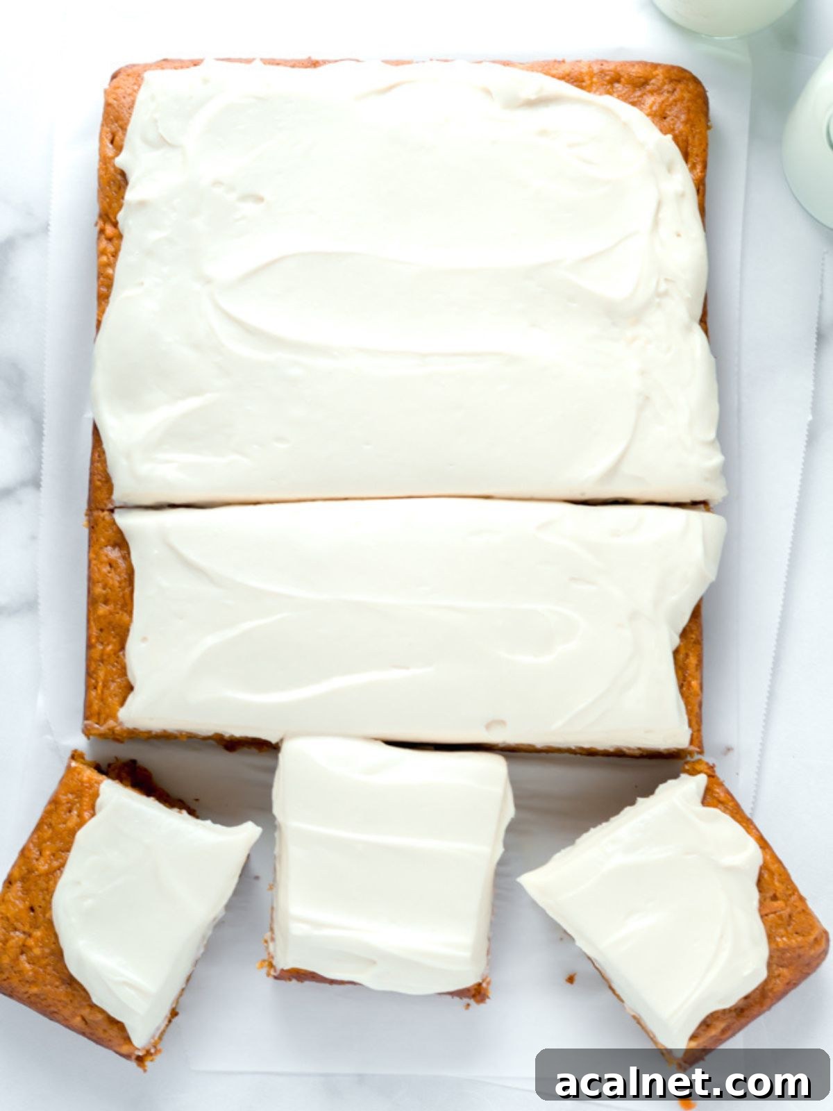 A pumpkin carrot sheet cake with brown sugar cream cheese frosting cut into slices. 