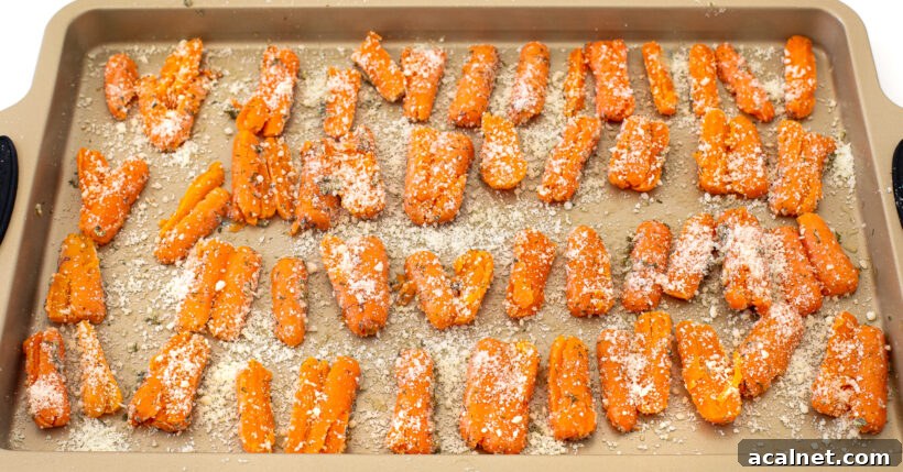Smashed carrots sprinkled with parmesan on a baking sheet. 