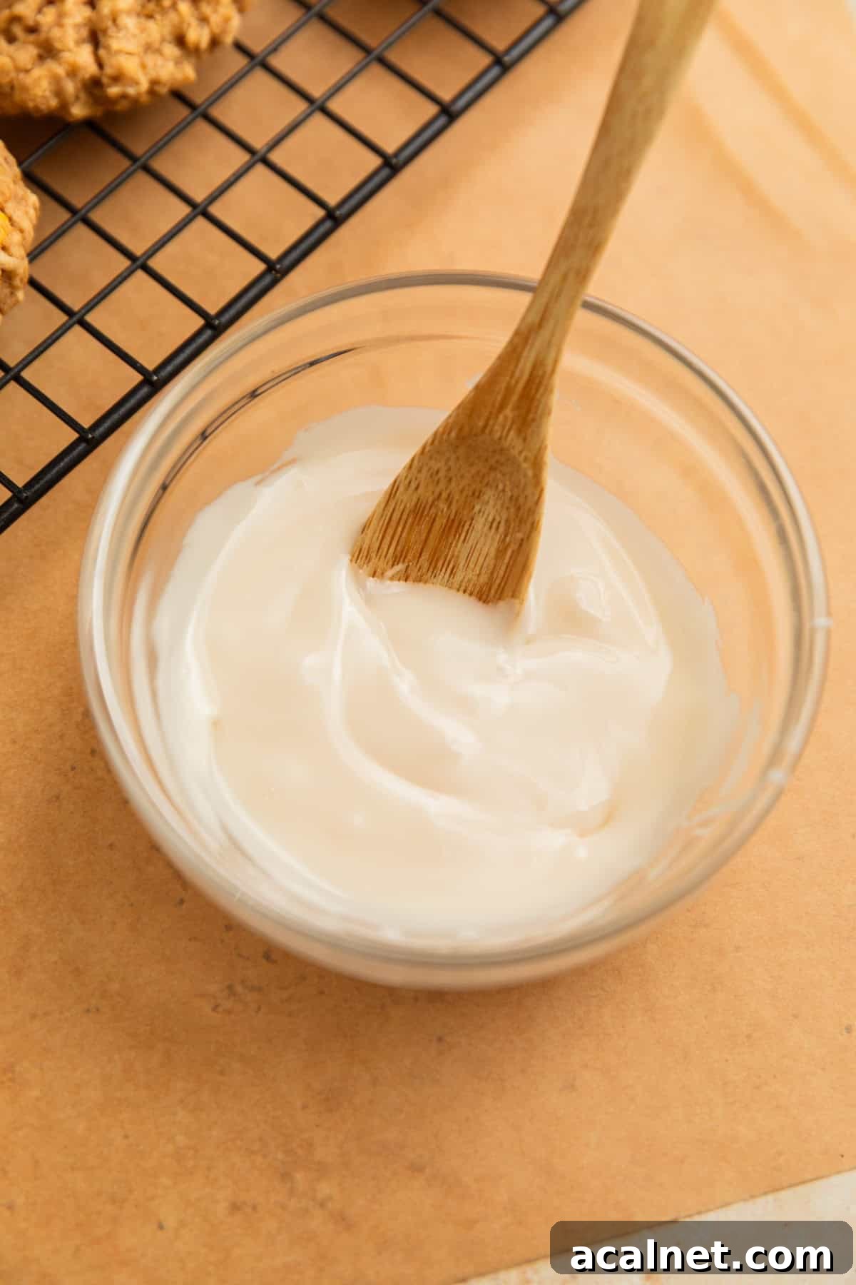 Icing glaze in bowl with wood spoon.