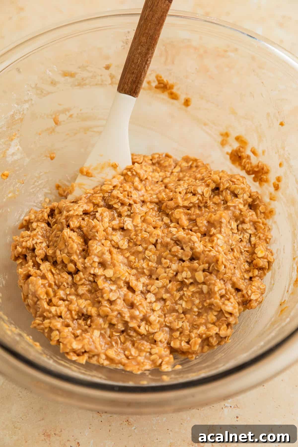 Cinnamon oatmeal cookie dough in bowl with spatula.
