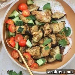 brown bowl with tofu, eggplant, tomato, and white sauce