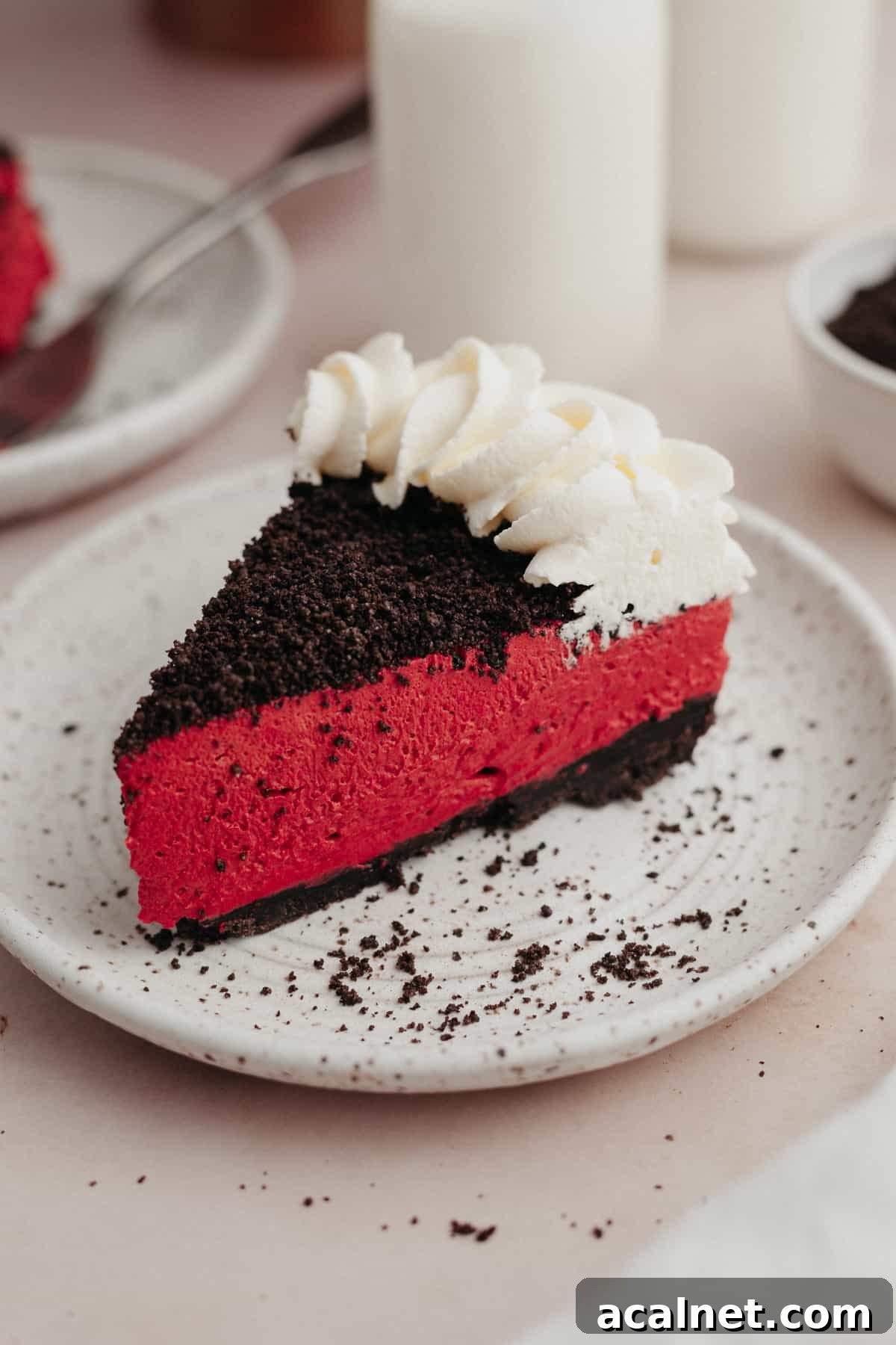A slice of red velvet oreo cheesecake on a small white plate.