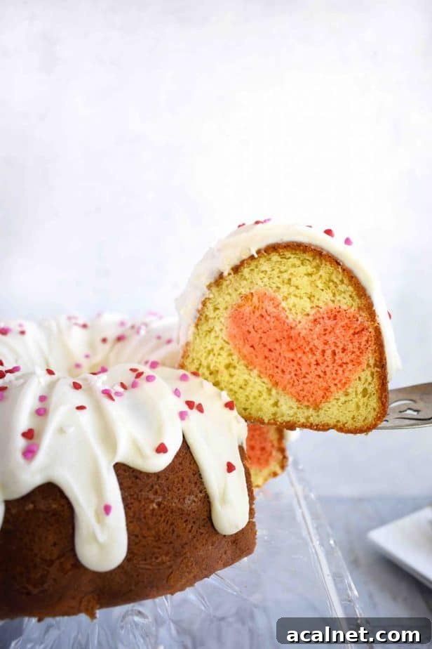 cake server lifting slice of bundt cake with heart inside off of cake place