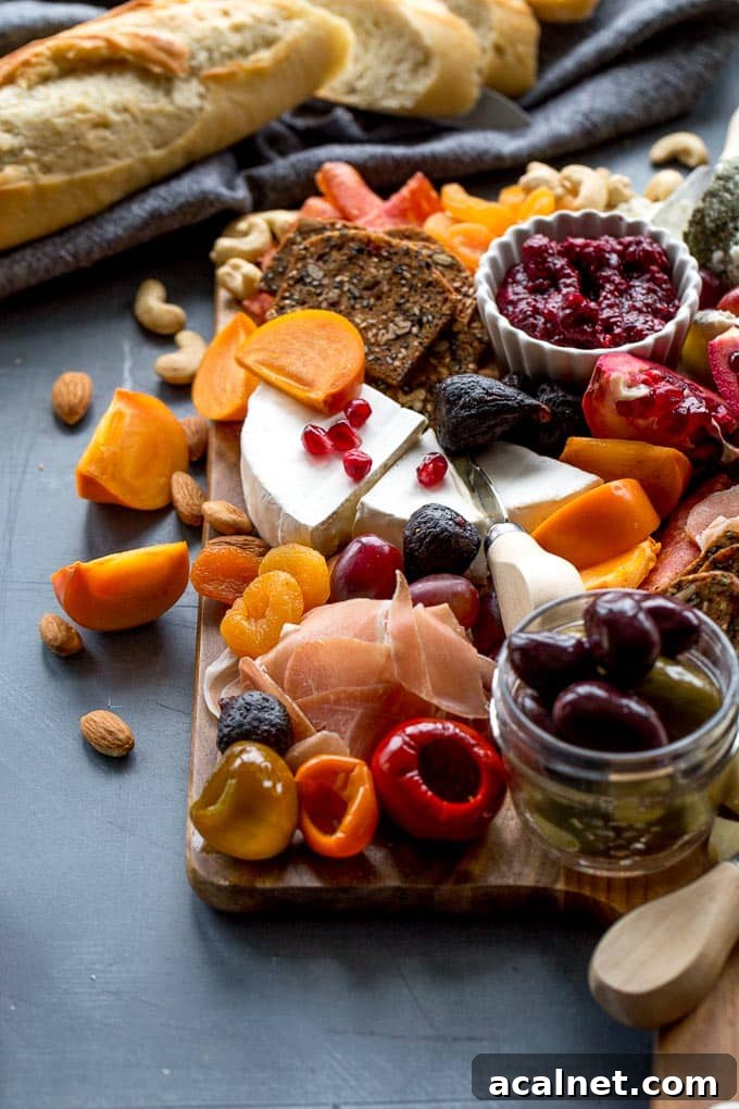 Side view of cheese, meats and fruit on a wooden board.