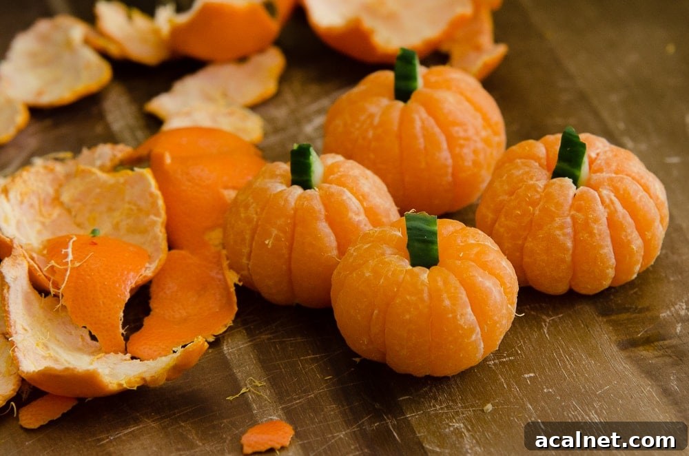 Peeled clementines on a wooden chopping board looking like pumpkins with cucumber stalks
