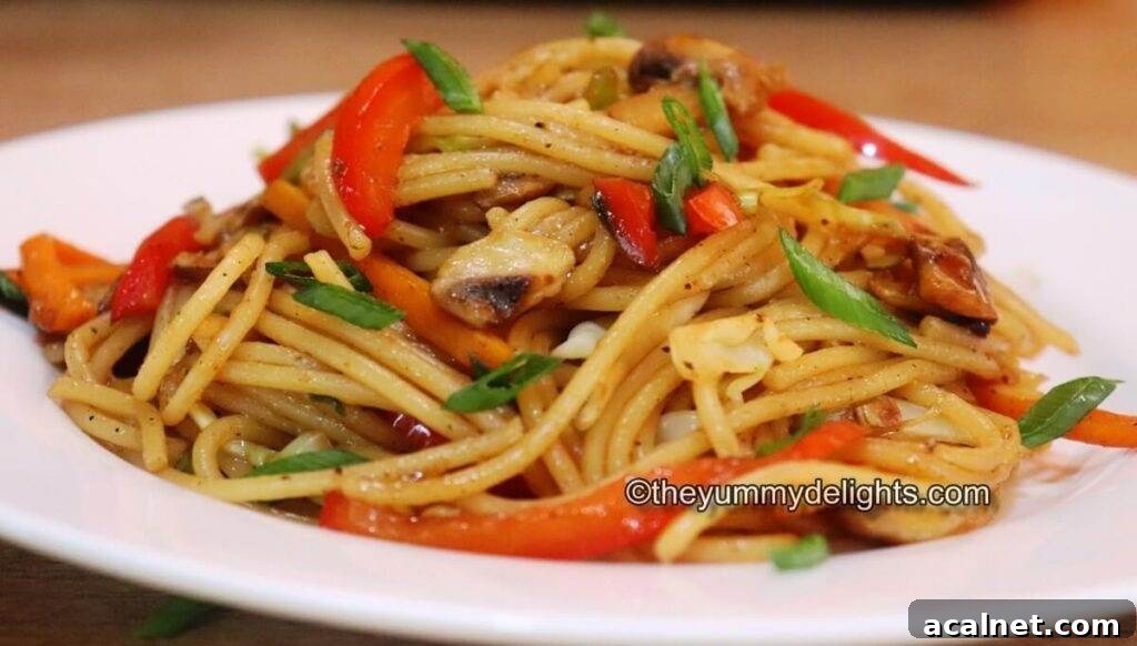 side view of veggie lo mein served on a white plate.