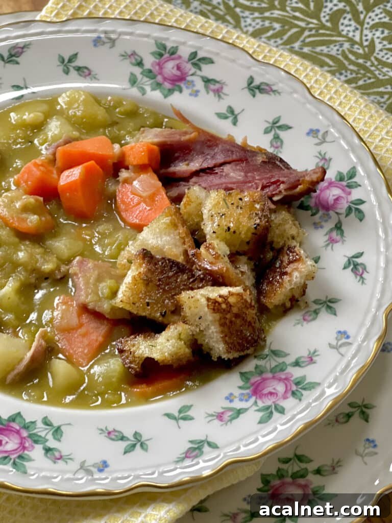 Split Pea and Ham Soup with Potatoes in decorative bowl topped with toast croutons.