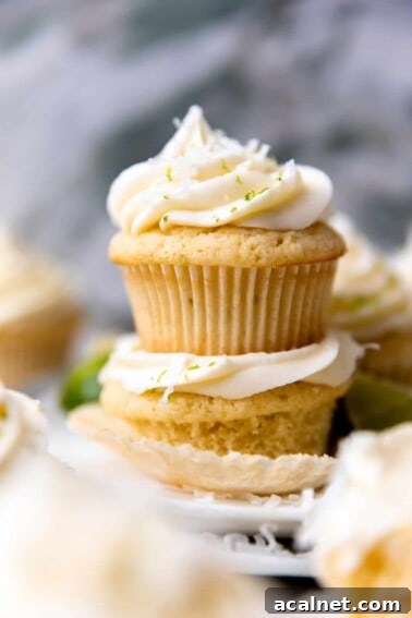 Stacked coconut lime cupcakes topped with coconut cream cheese frosting.