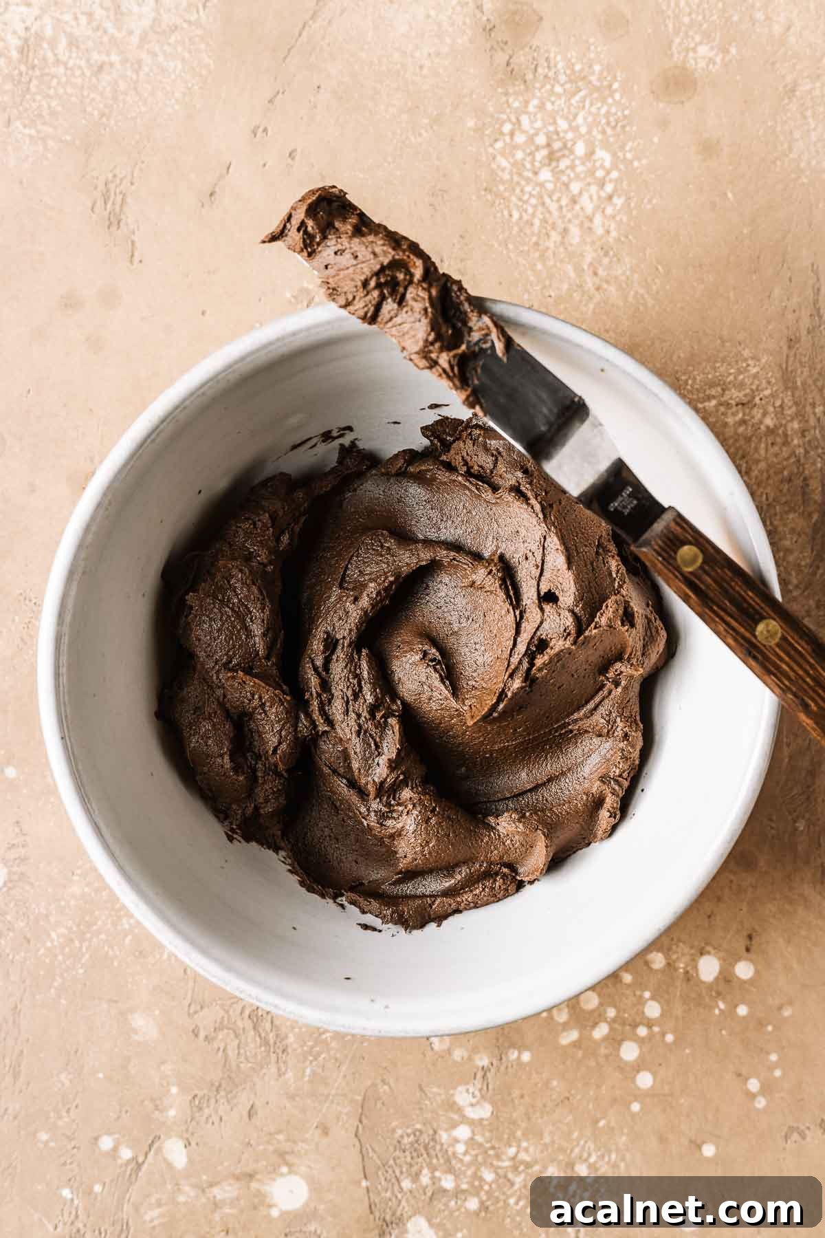 A bowl of whipped chocolate ganache with a small offset spatula.