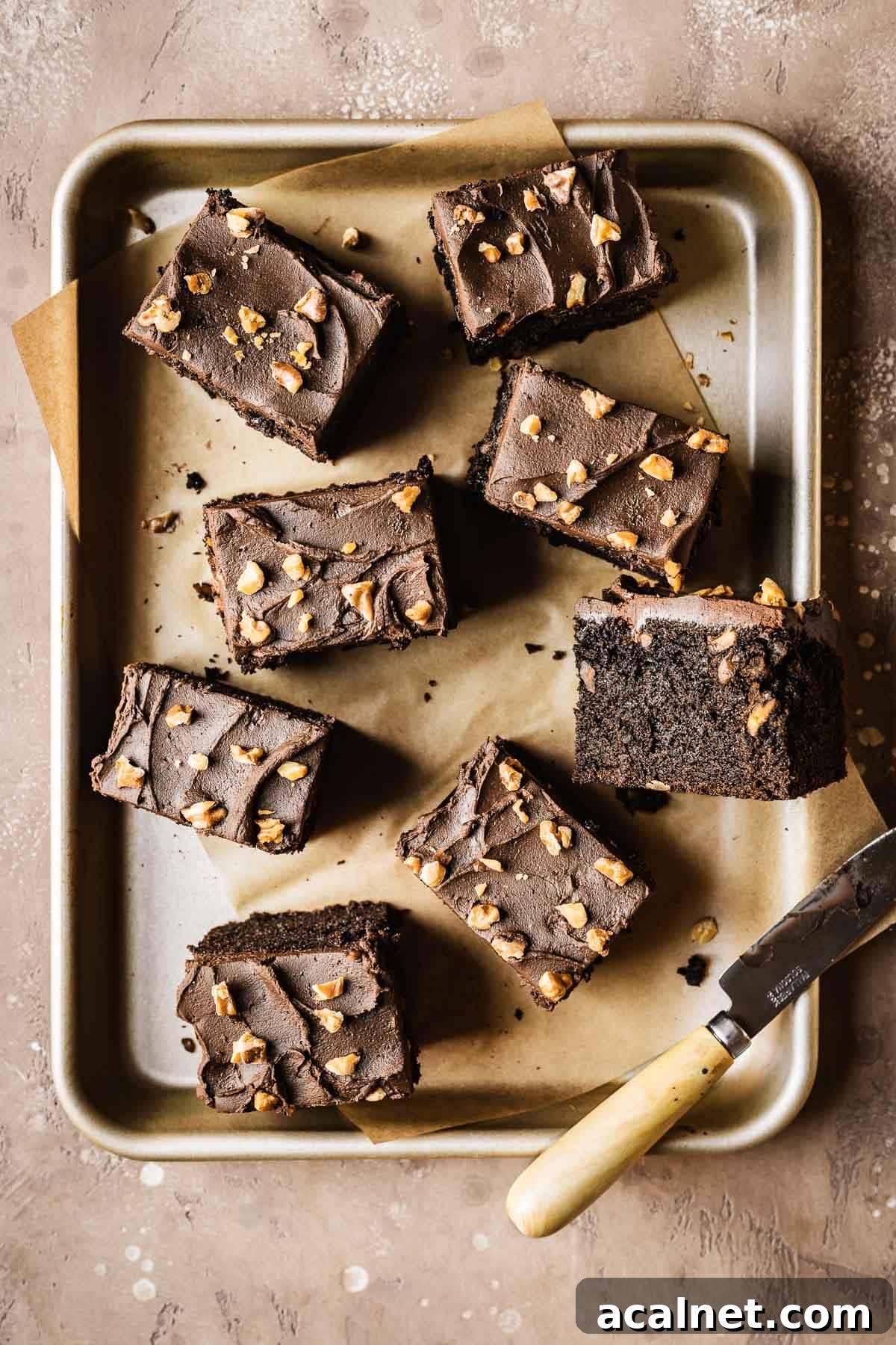 Slices of chocolate cake on a small gold baking pan lined with brown parchment paper.