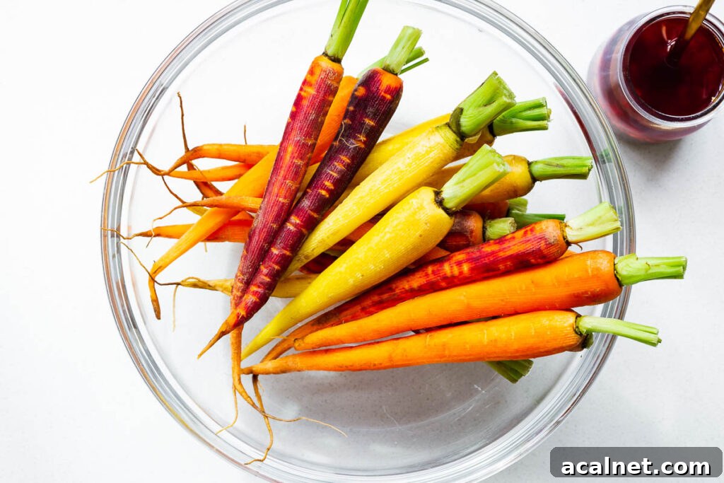 Prepared rainbow carrots in a large mixing bowl, ready to be tossed in a harissa maple marinade.