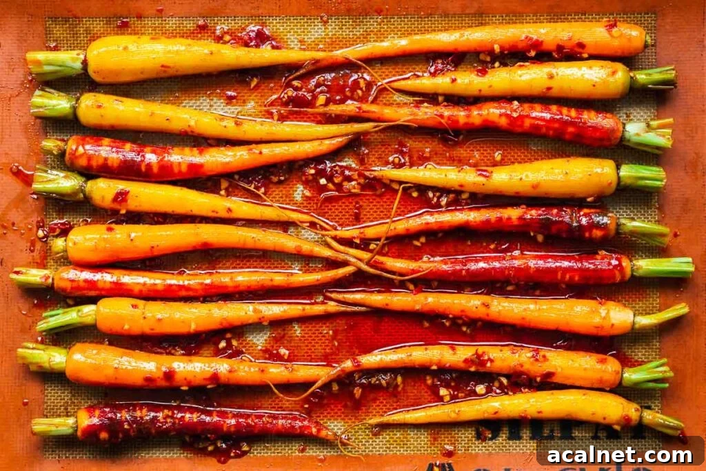 Carrots tossed in harissa marinade and arranged on a baking sheet in an even layer.