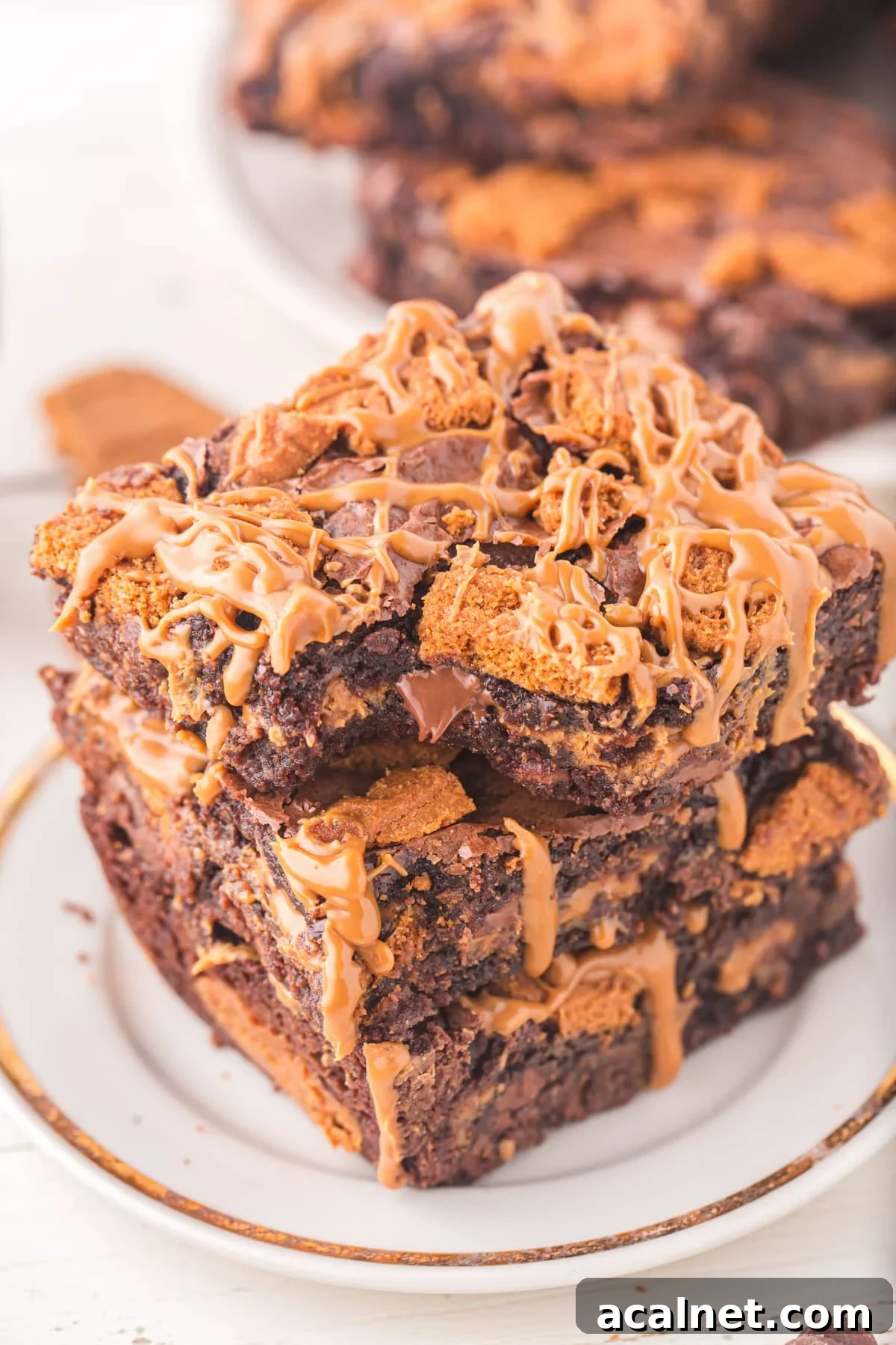 A stack of three brownies topped with crushed Biscoff cookies and cookie butter.