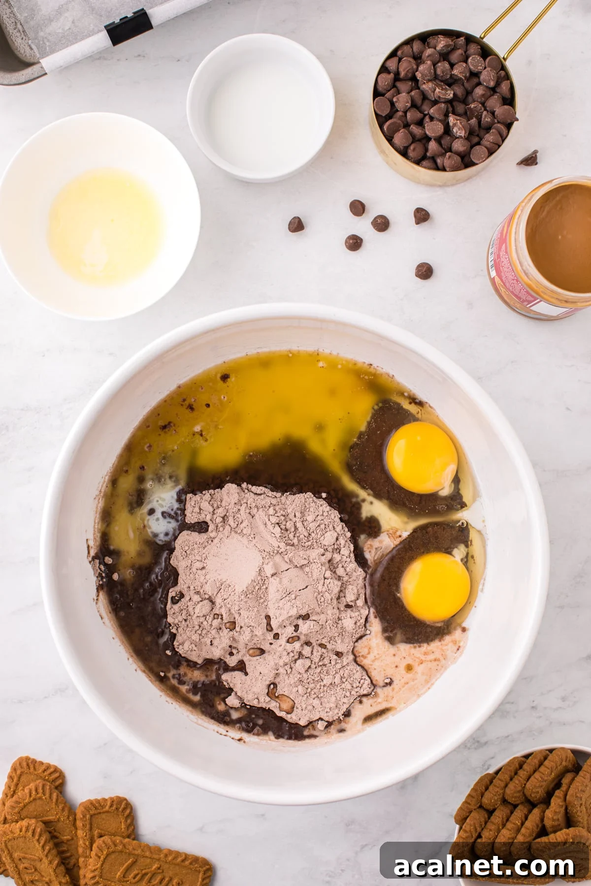 A bowl filed with brownie mix, eggs, milk, and melted butter.