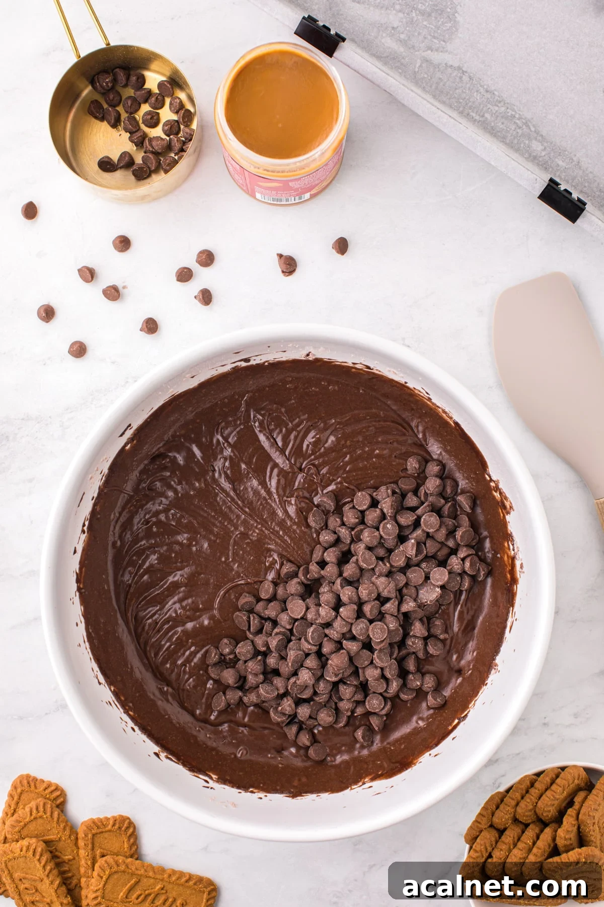A bowl of brownie batter with chocolate chips added into the batter.