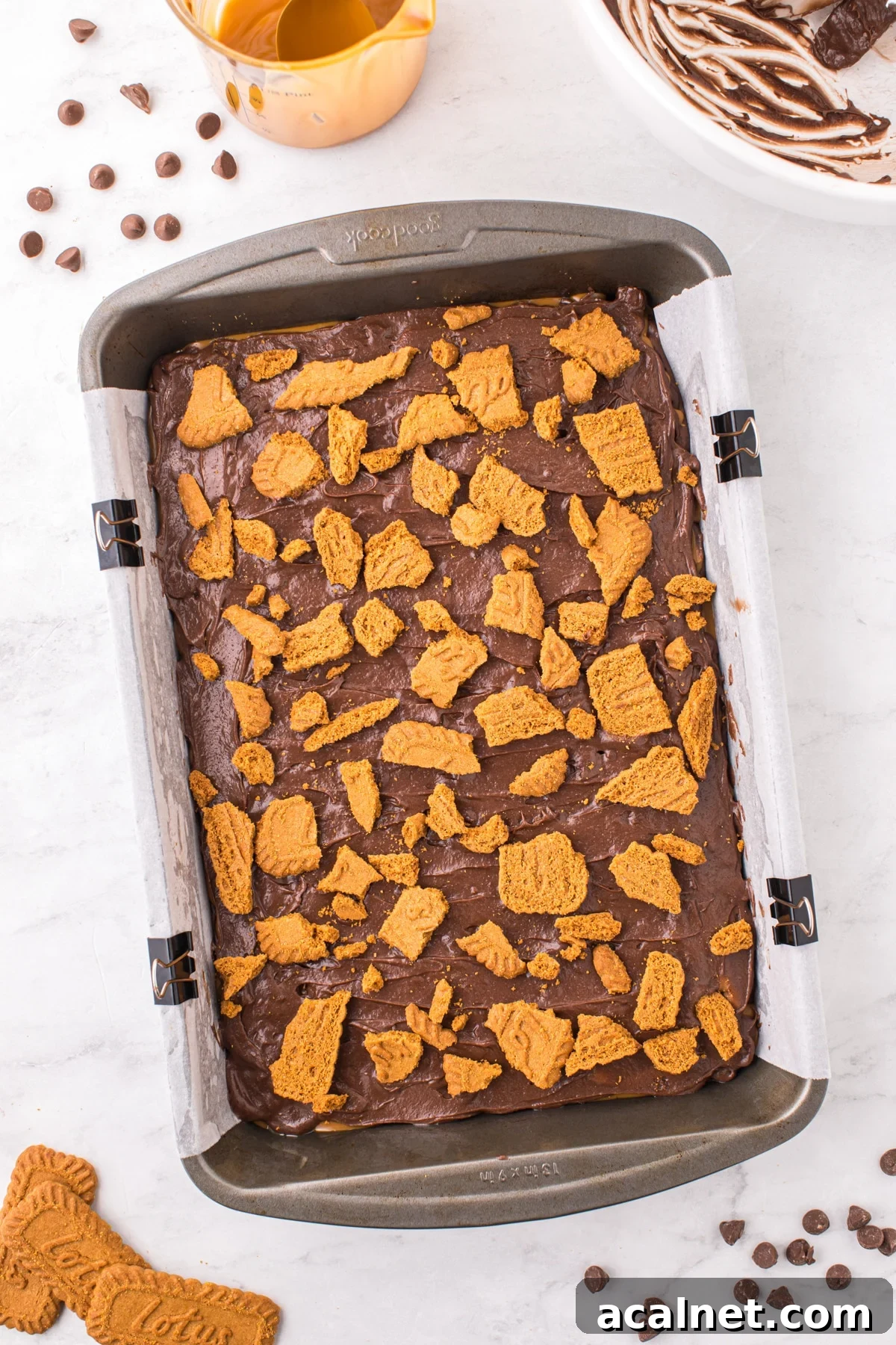 A baking pan filled with brownie batter and topped with cookie pieces.