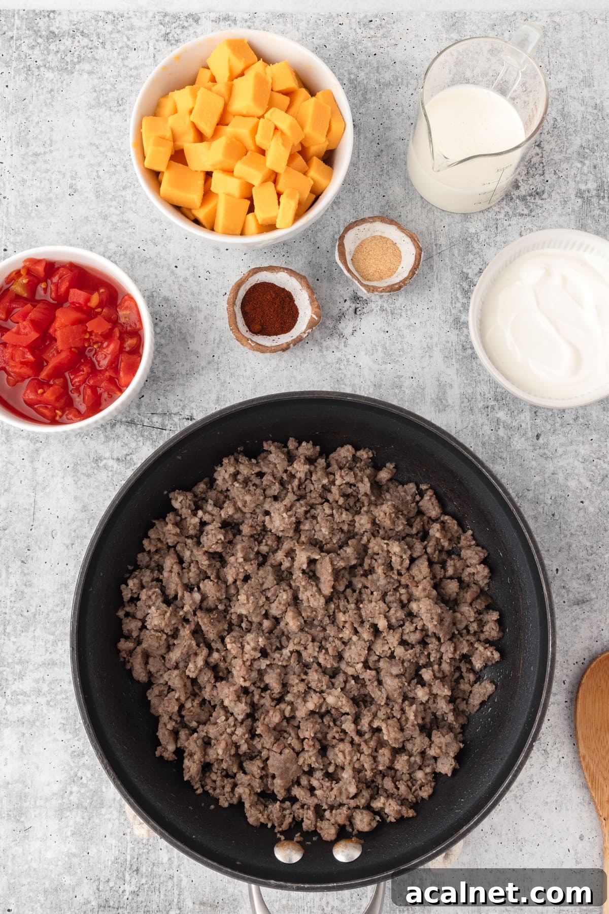  Velveeta Sausage Cheese Dip process shot shown. cooked sausgae in a black skillet with cubed cheese and tomatoes, seasonings on the side.