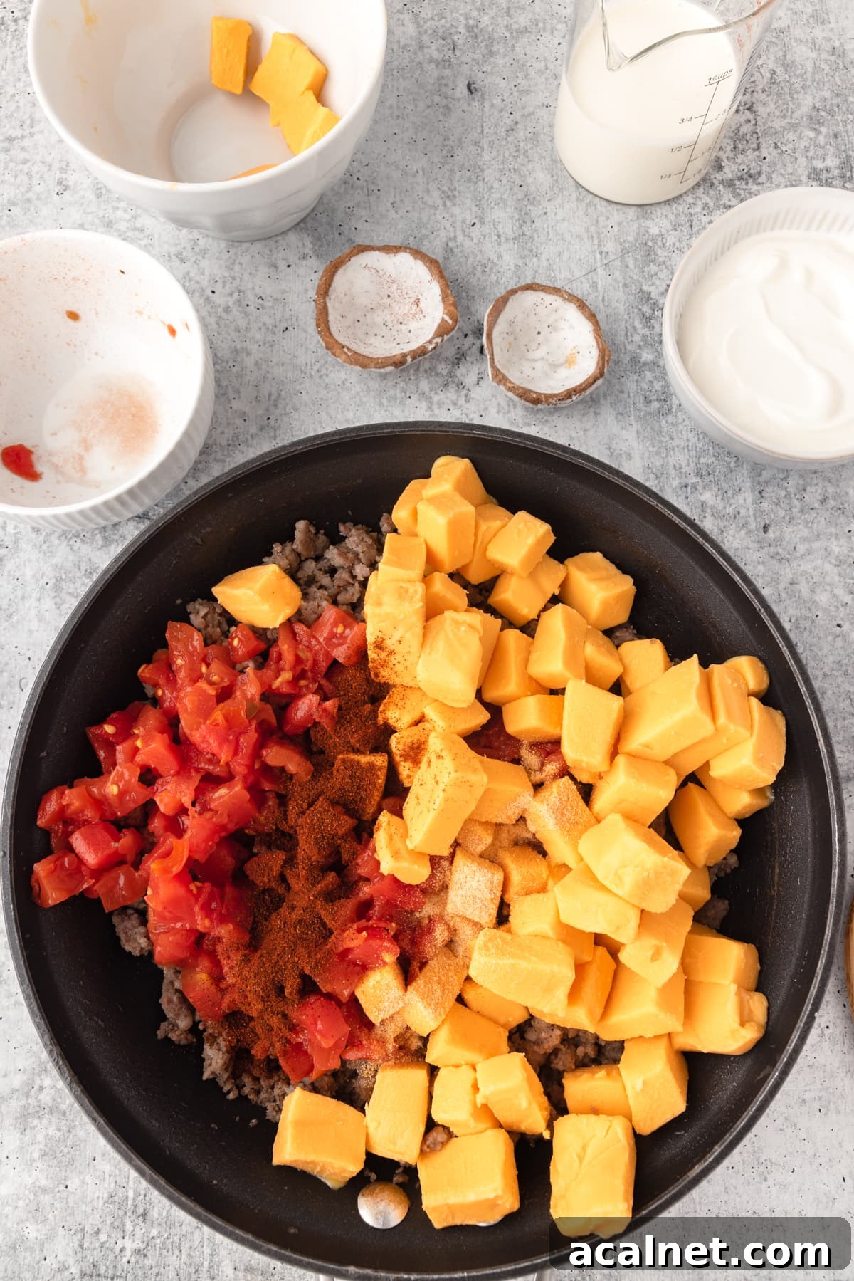 Velveeta Sausage Cheese Dip ingredients shown together in a skillet, cubed cheese, rotel and sausage