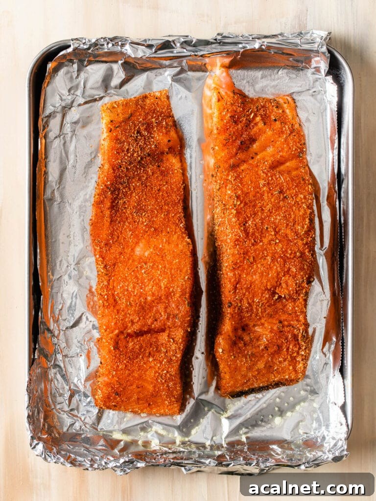 Blackened Baked Salmon with Creamy Cheddar Grits 3 two pieces of salmon seasoned with blackening seasoning on a sheet pan