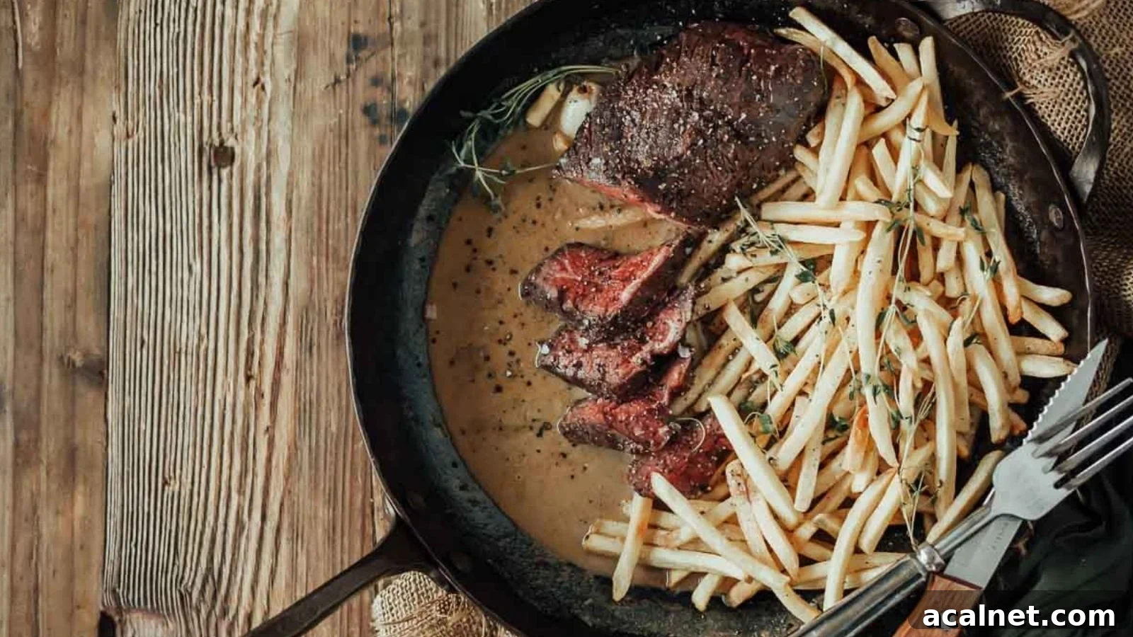 Sous vide hanger steak frites with sliced steak and crispy fries arranged beside it.