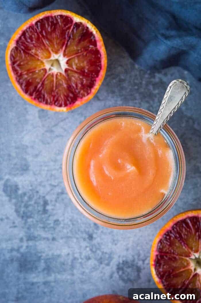 Vegan Blood Orange Curd Recipe — Silky, Zesty Spread 9 close up of a jar of vegan blood orange curd with a spoon in it and sliced blood oranges.