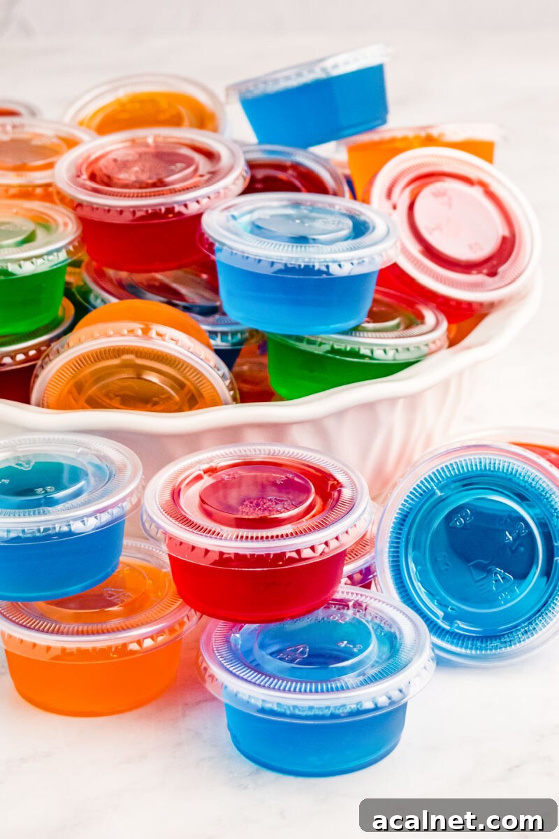 Vodka Jello Shots are a classic party cocktail that's easy to whip up and can be made in any flavor of Jello you love! Be sure to make a bunch, they go fast! cherry and blue berry jello shots stacked next to a bowl of shots