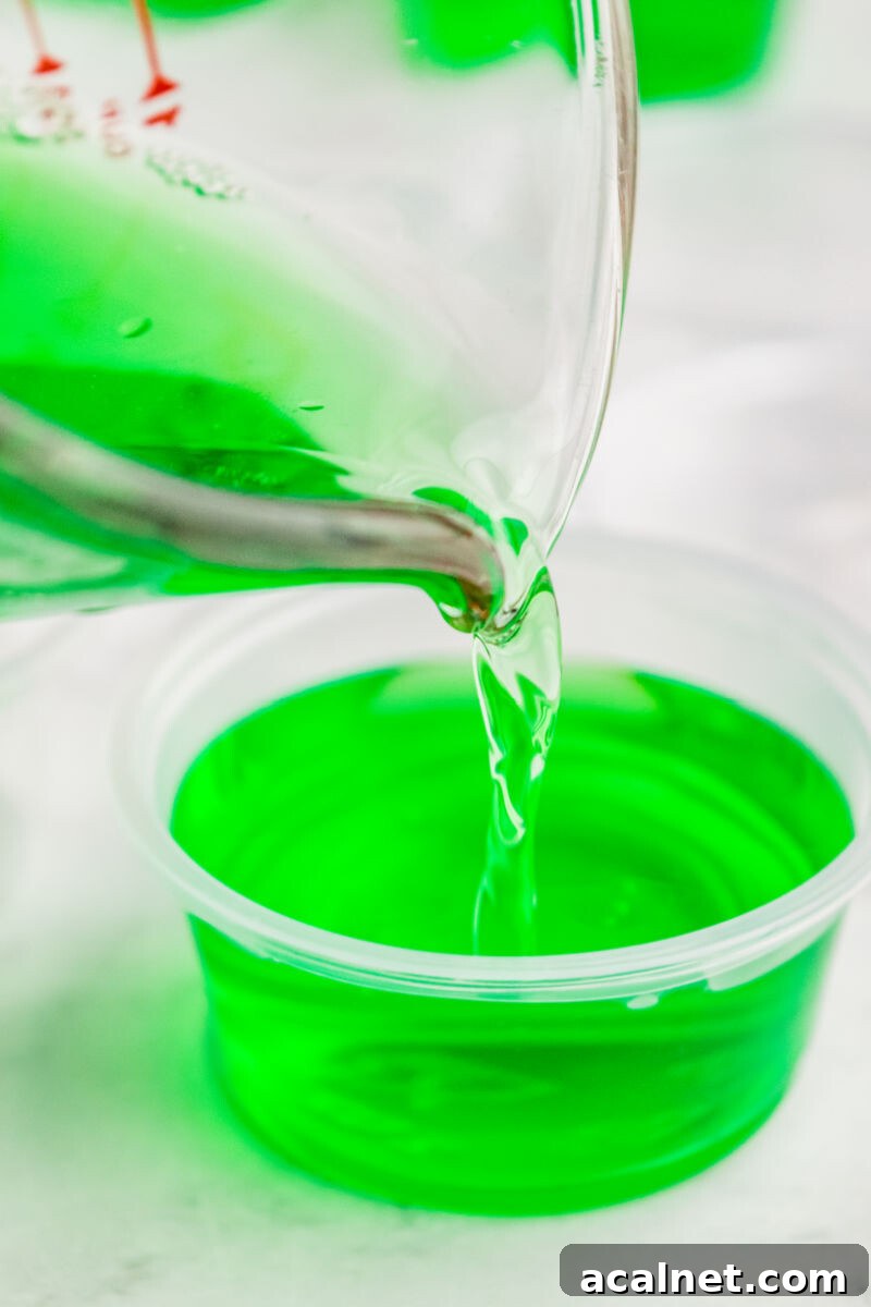 Vodka Jello Shot Recipe: Party-Friendly Jiggly Cocktails 5 jello shot mix being poured into a small plastic cup
