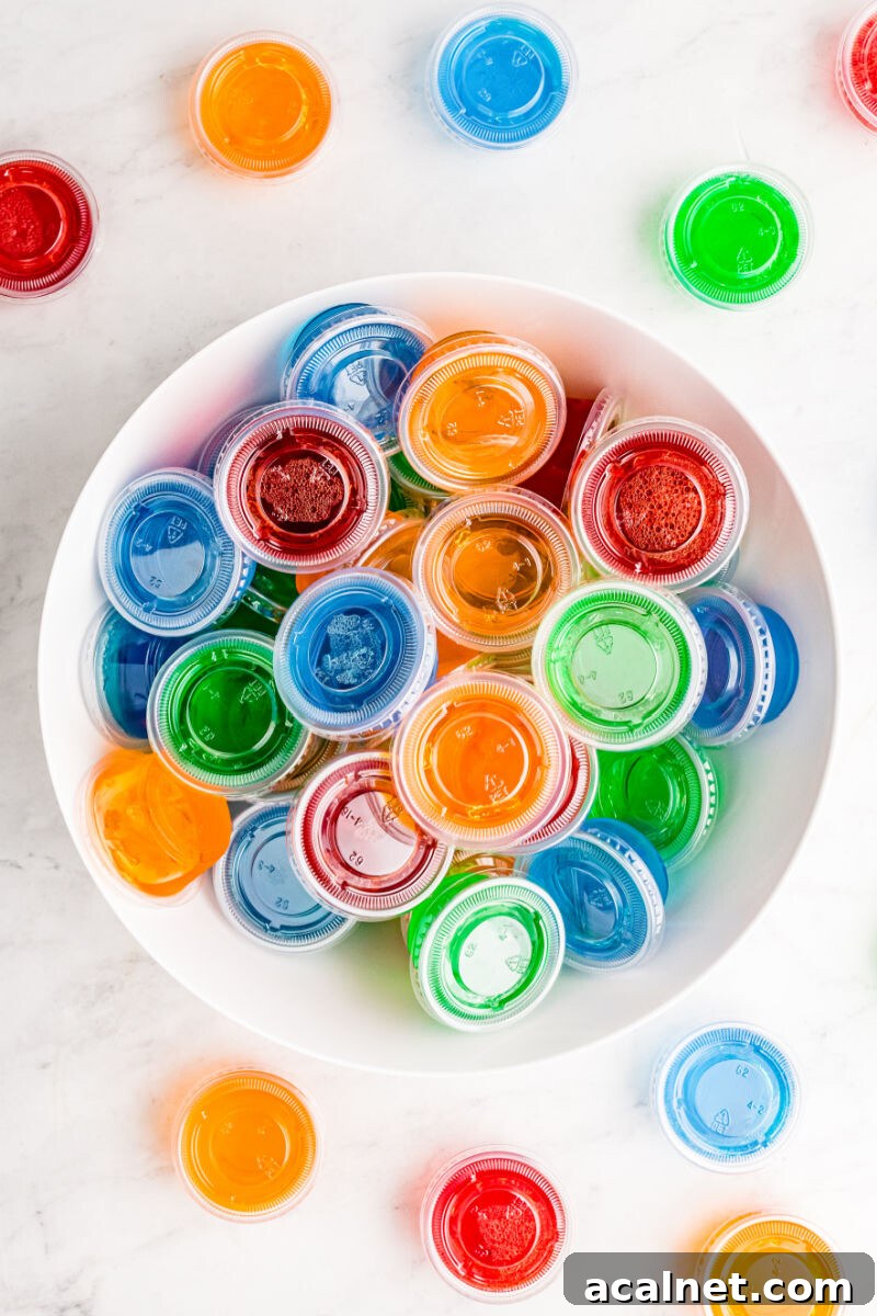 Vodka Jello Shots are a classic party cocktail that's easy to whip up and can be made in any flavor of Jello you love! Be sure to make a bunch, they go fast! looking down at a bowl of jello shots with cups around it