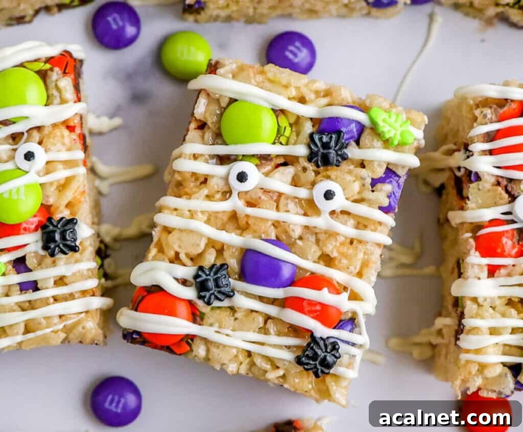 Close up of Rice Krispie Treats decorated with Halloween M&Ms, candy eyes and white chocolate drizzle.
