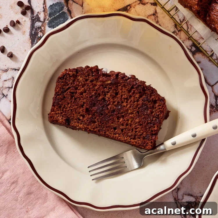 A slice of chocolate olive oil banana bread on a plate with a fork.