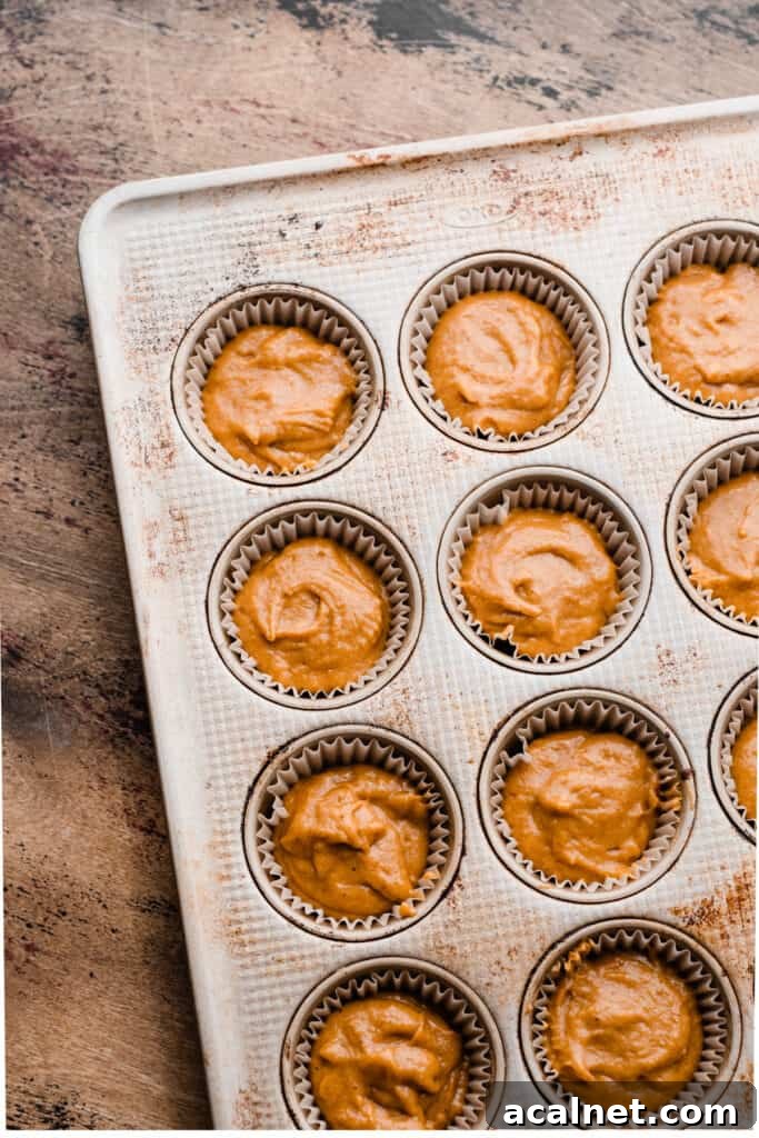 A muffin pan with paper liners filled with batter.