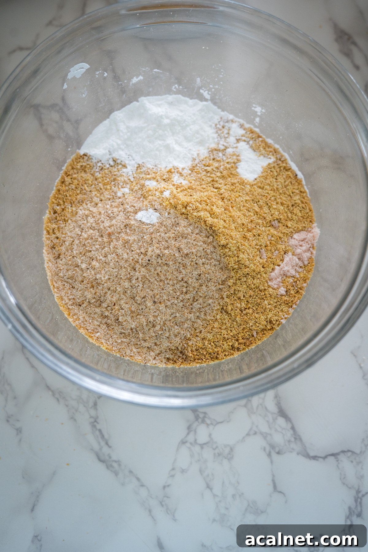A glass bowl filled with flour, sugar, and salt for flaxseed rolls.
