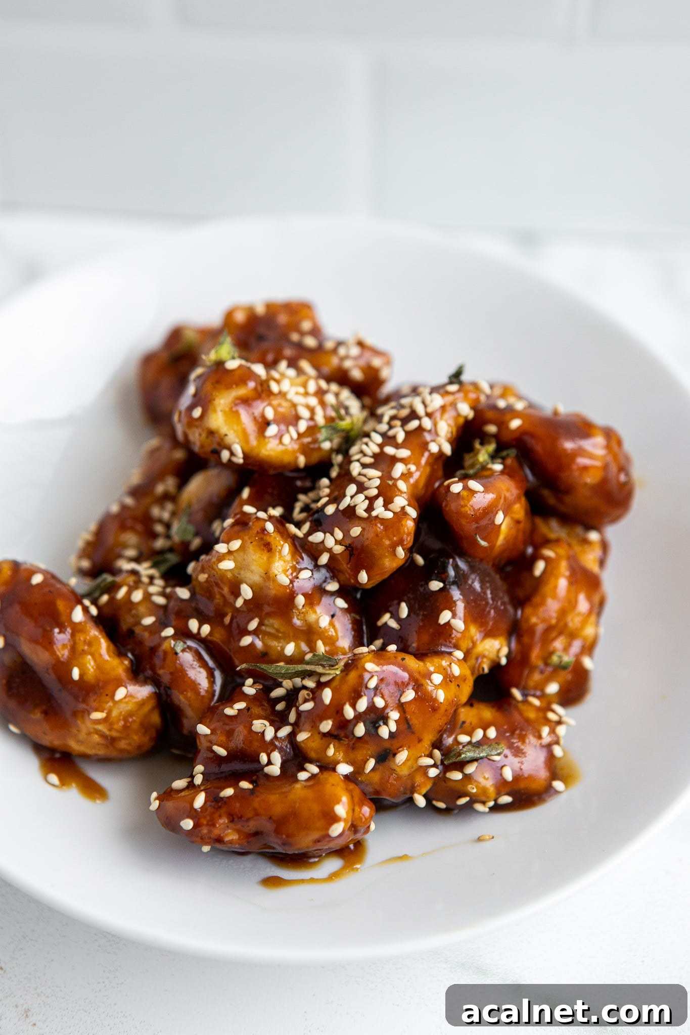 Crispy Air Fryer Sesame Chicken Bites — 62g Protein Per Serving 6 Side view of crispy air fryer sesame chicken recipe on white plate with sesame seeds — gluten free high protein dinner