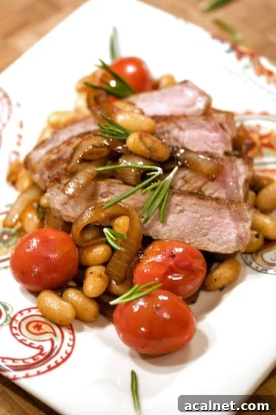 Sliced steak with white beans and tomatoes.