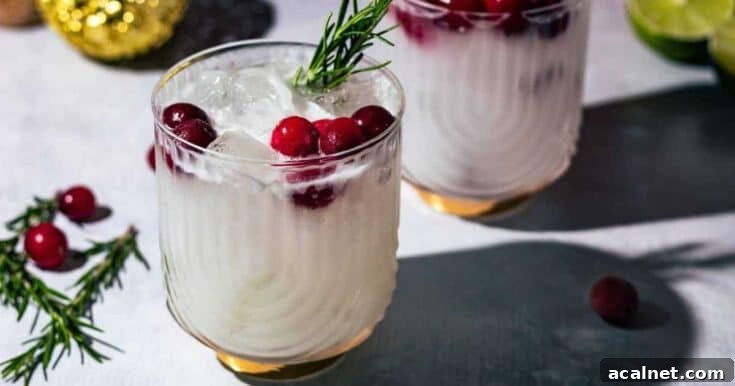 A white Christmas margarita garnished with cranberries and rosemary.