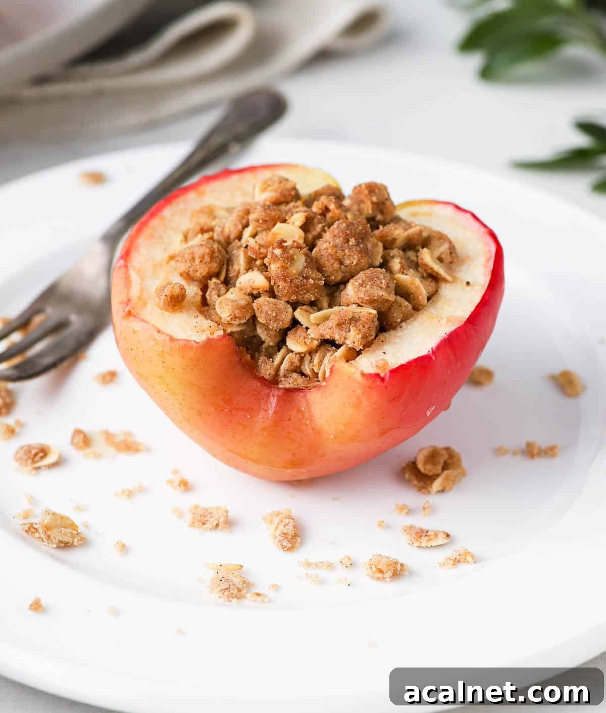 Remoska Baked Apples with Cinnamon Crumble 7 One apple on a small white plate with a fork.