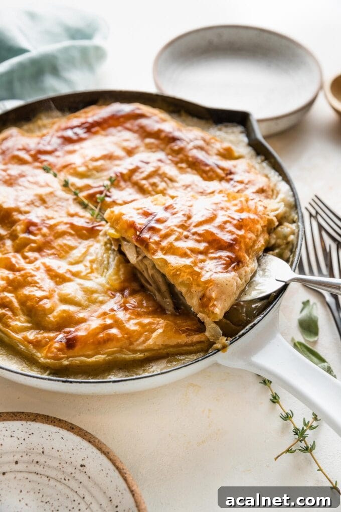 Serving spatula lifting one piece of turkey pot pie out from a cast iron skillet.
