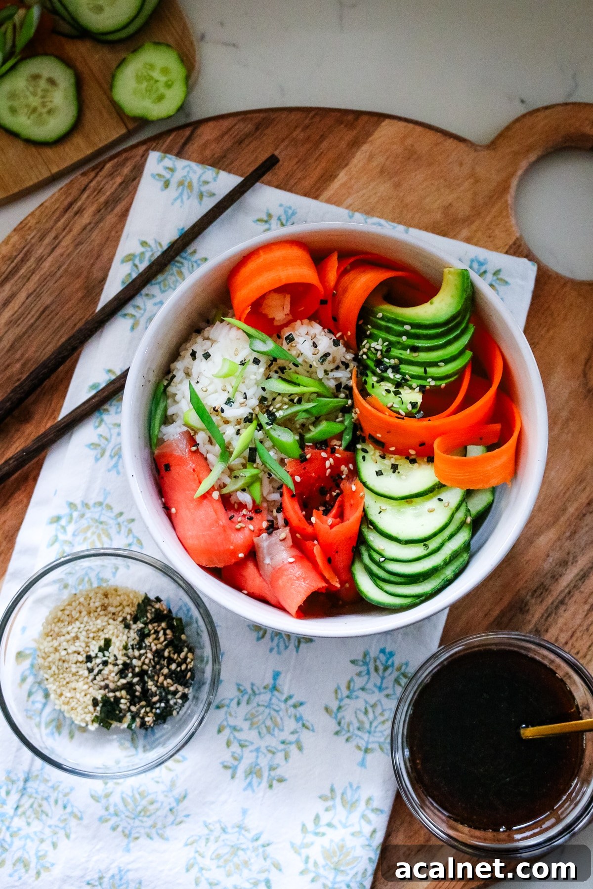 Smoked Salmon Poke Bowl with Avocado, Sesame and Lime 2 Smoked salmon in a white bowl, served with sliced cucumber, sesame seeds, and soy sauce on the side.