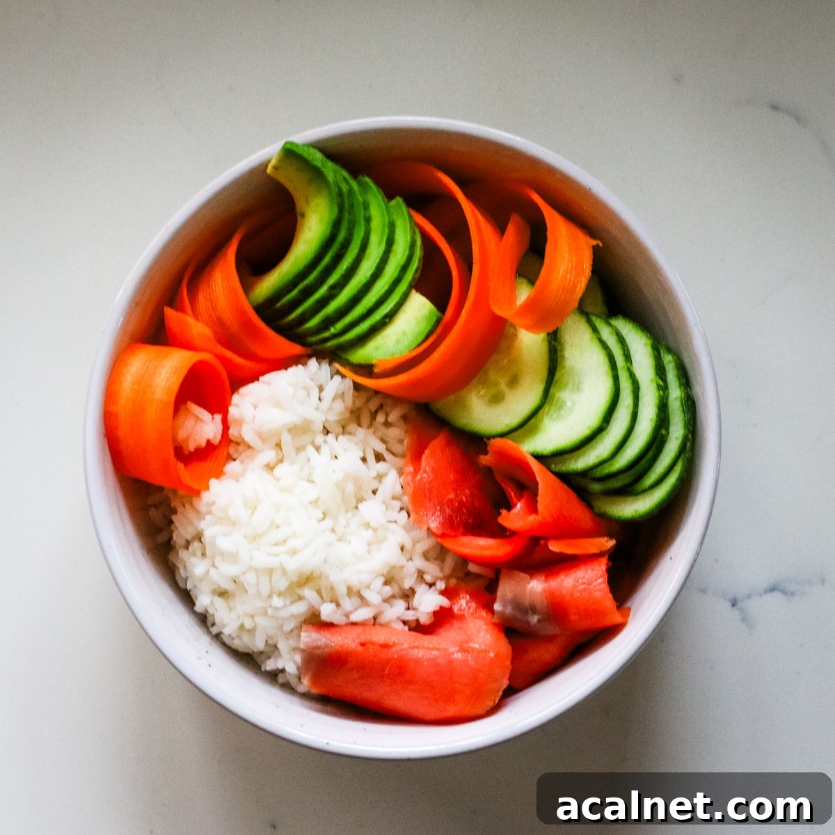 Smoked Salmon Poke Bowl with Avocado, Sesame and Lime 7 Assembling smoked salmon in a white bowl.