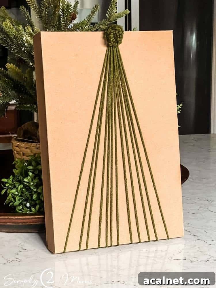 Kraft box with yarn arranged into a Christmas tree shape and a mini pompom topper