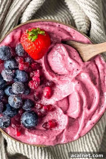 A coconut bowl filled with an acai smoothie bowl, topped with fruit.