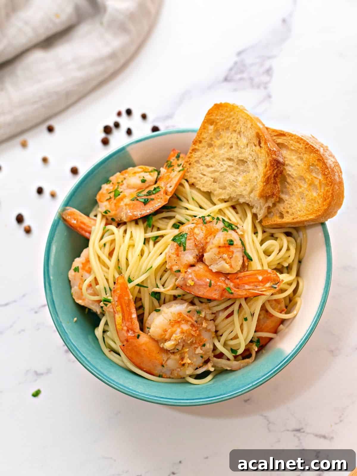 Bowl of Shrimp Scampi tossed with Angel Hair Pasta with garlic toast served on the side.