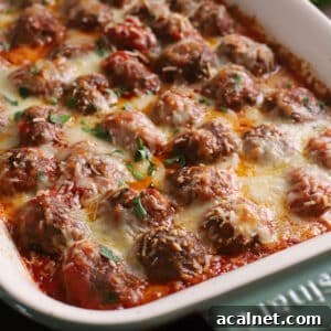 Baked meatballs in a green ceramic casserole topped with melted cheese.