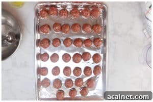 Shaped meatballs on a foil lined baking sheet.