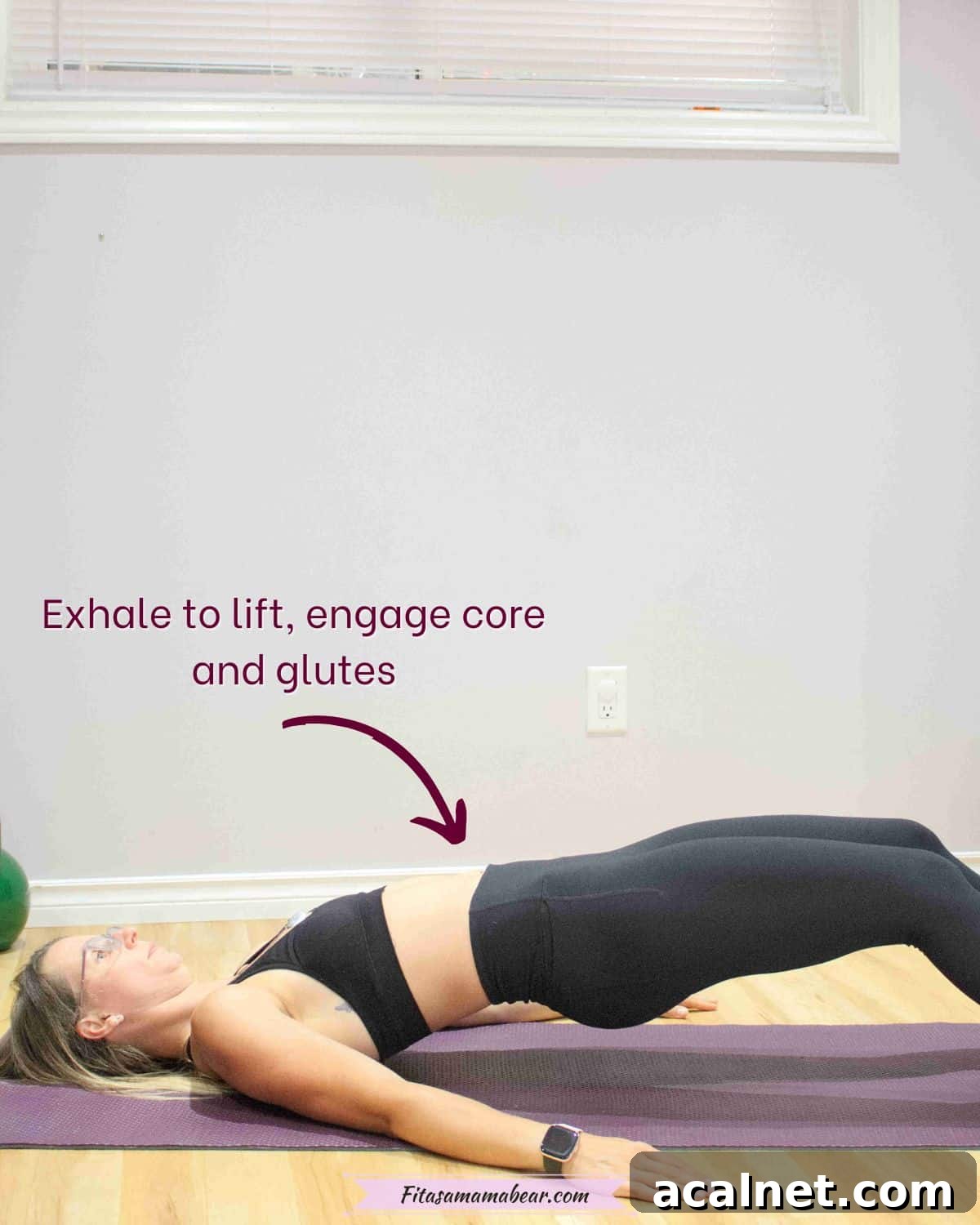 Woman in black sports bra and pants laying on the ground with her legs semi extended and lifting her hips