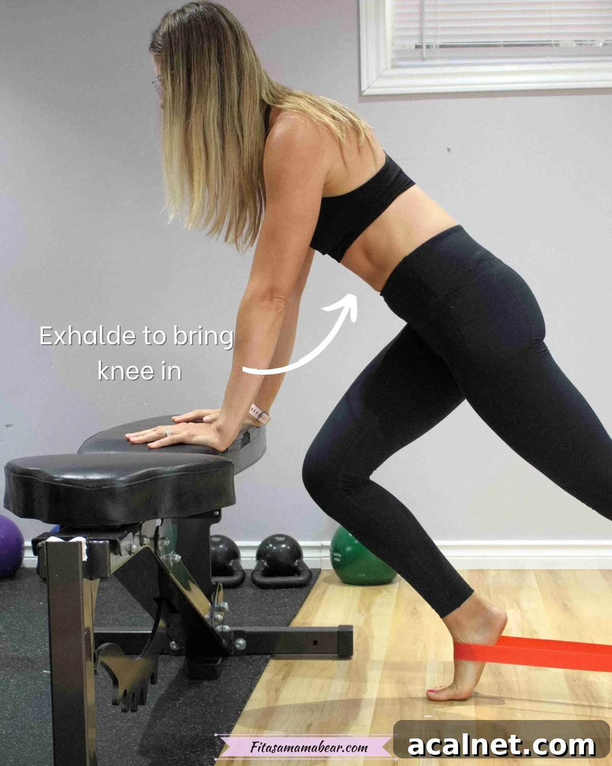 Woman in black sports bra and pants in a plank on a bench with one leg in toward the bench and a red mini loop around her feet