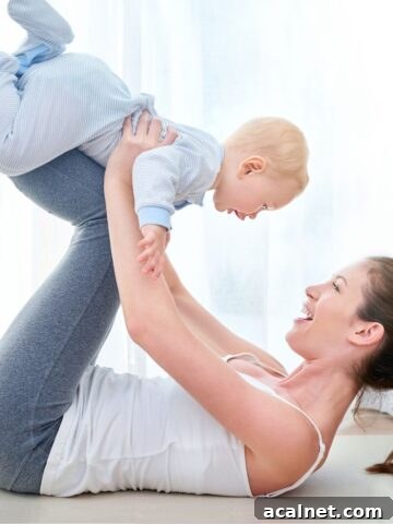 Mom laying on ground with baby on her legs in the air.