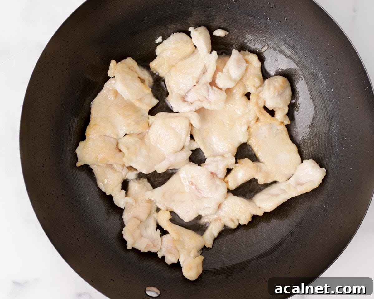 Searing the chicken in a pan with oil.